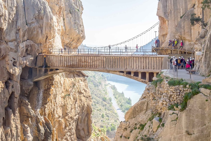 A suspension bridge over a canyon with people walking on it. 1