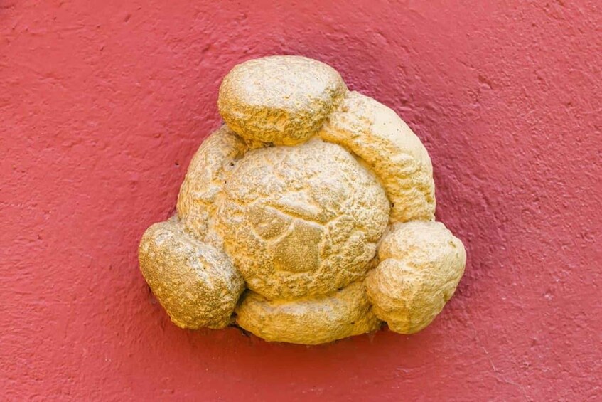 A cluster of golden-brown, textured objects against a red wall. 2