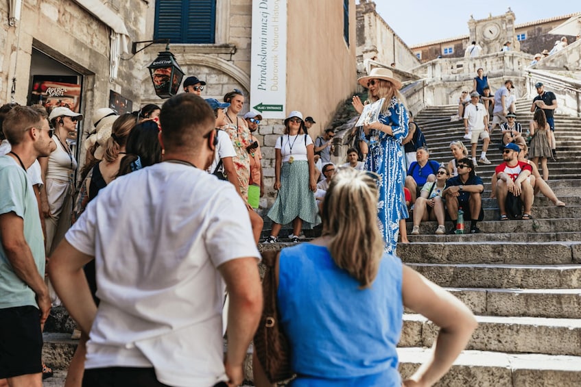 A crowd gathered on stone steps in a historic town square, with a banner reading "Pridolomni muzej Dubrovnik". 3