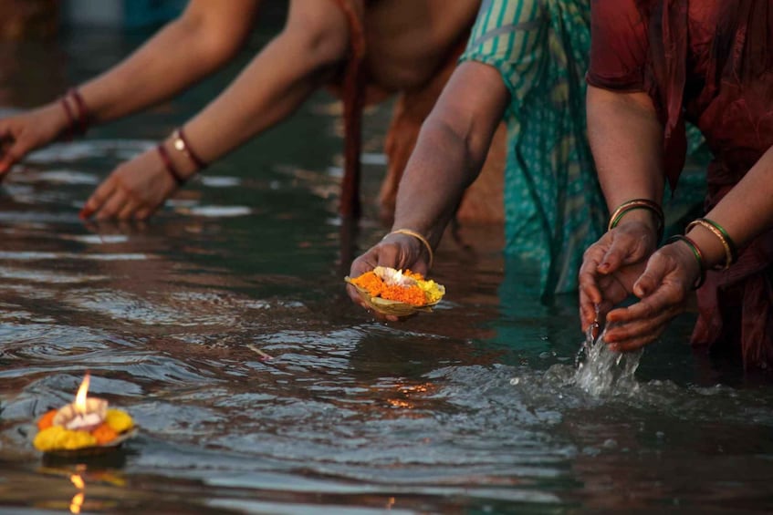 Personas realizando un ritual ofreciendo flores a un cuerpo de agua. 5