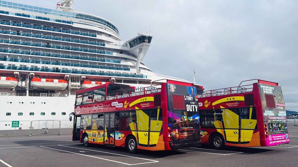 Two double-decker buses parked in front of a cruise ship. 2