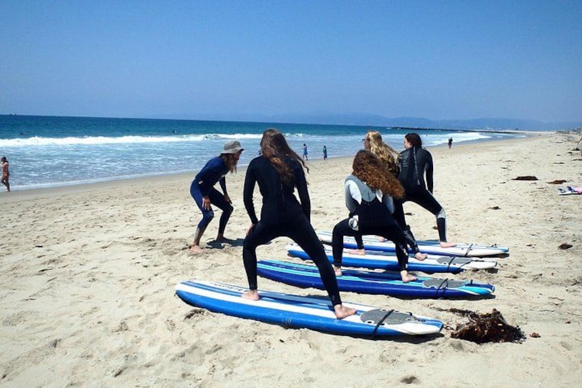 En gruppe mennesker i våddragter på en strand med surfboards. 1