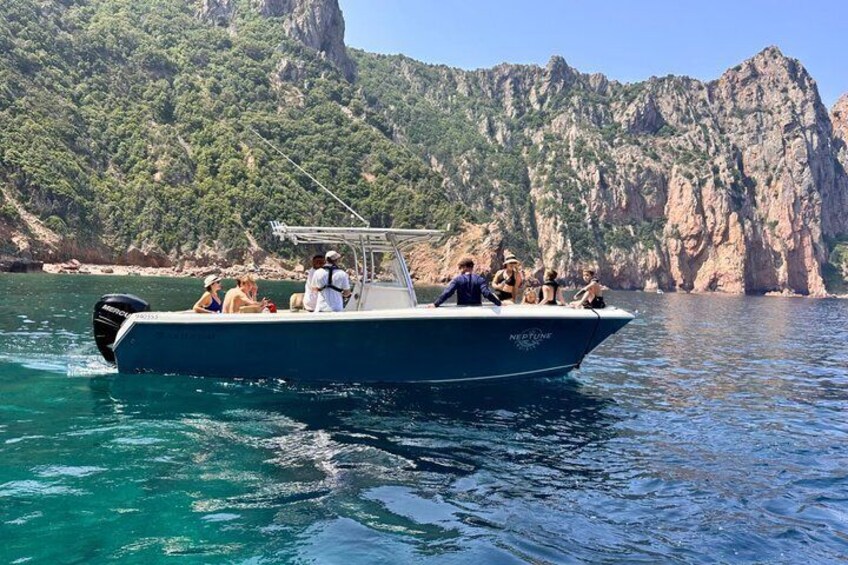 A boat with people on a clear day, surrounded by rocky cliffs and greenery. 4