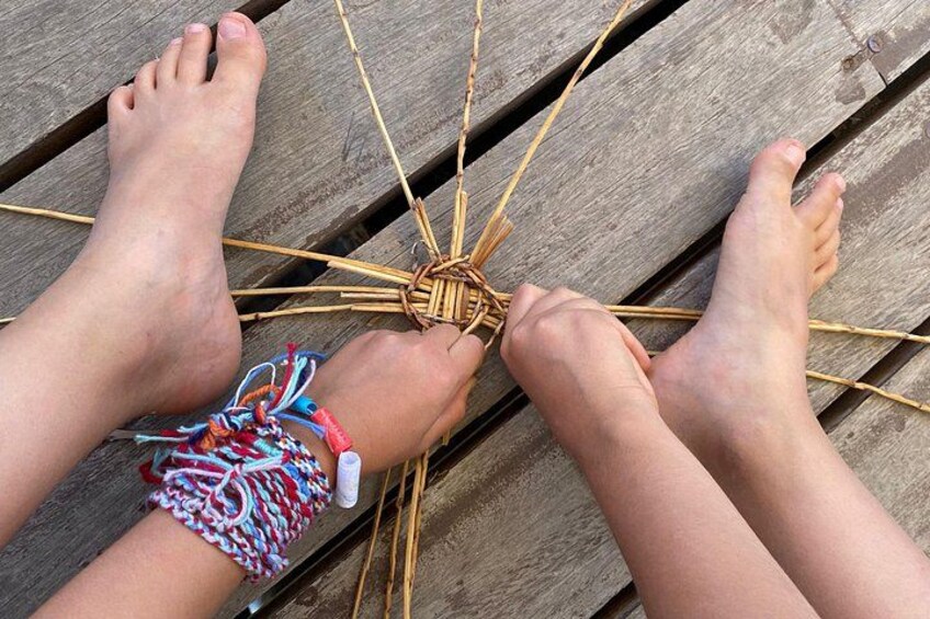A person's feet weaving a basket on a wooden surface. 3