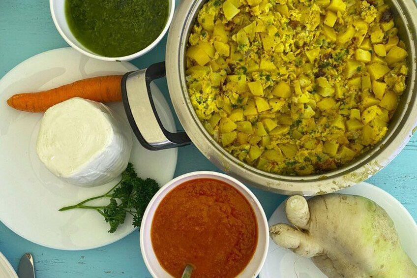A variety of dishes including a pot of diced potatoes, a bowl of red sauce, a carrot, a piece of cheese, and a ginger root. 2