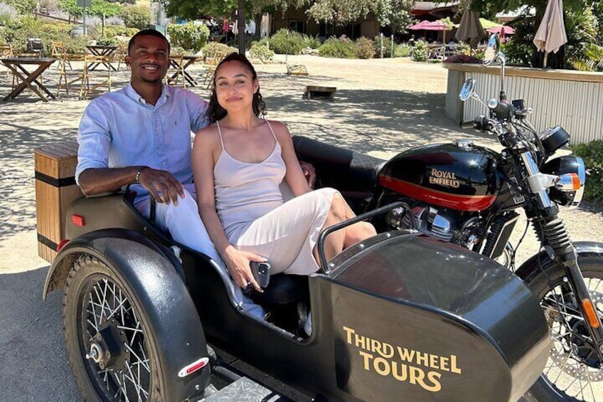A man and woman sitting on a motorcycle with a sidecar labeled "THIRD WHEEL TOURS." 5