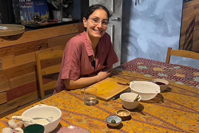 A person sitting at a table with various bowls and a cutting board. 4