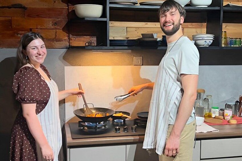 A kitchen with a stove, a woman cooking, and a man standing beside her. 5
