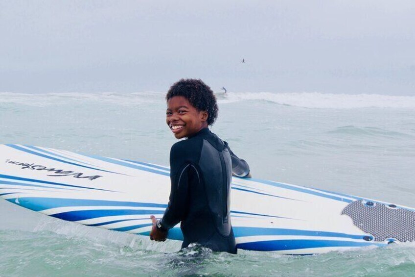 Boy smiles with his surfboard.