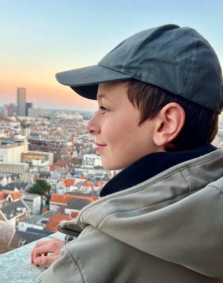 Une personne portant une casquette et une veste, qui surplombe un paysage urbain avec des bâtiments et un ciel dégagé. 5