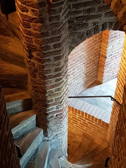 Un escalier en pierre avec une rampe métallique, menant à un niveau supérieur doté d’un toit en pente. 3