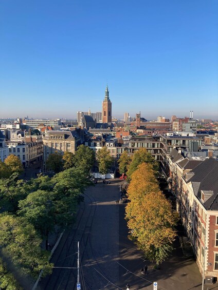 Une vue urbaine caractérisée par un imposant beffroi, des voies de tramway et des bâtiments historiques. 1