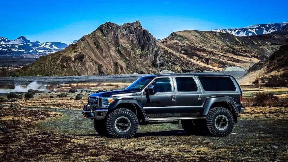A black SUV parked in a rugged outdoor setting with mountains in the background. 2