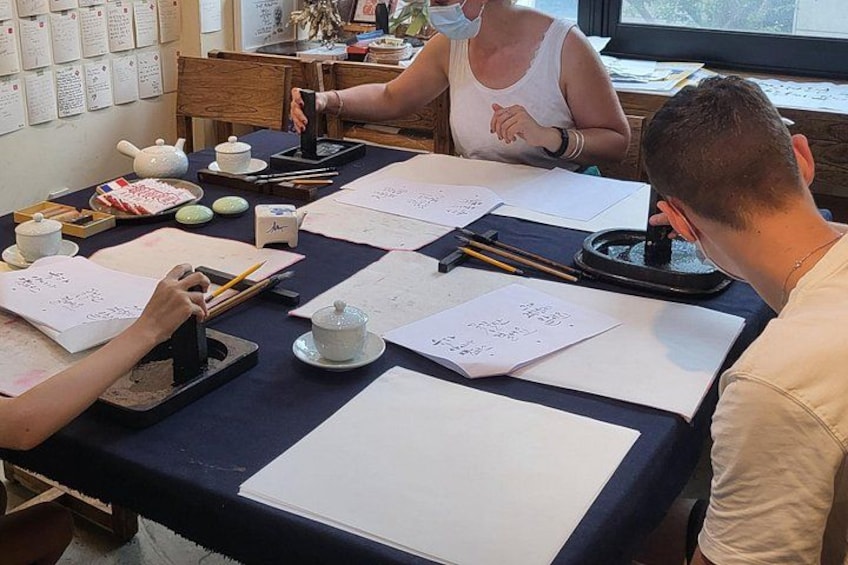 En grupp människor sitter vid ett bord med papper, en tekanna och en kopp. 2