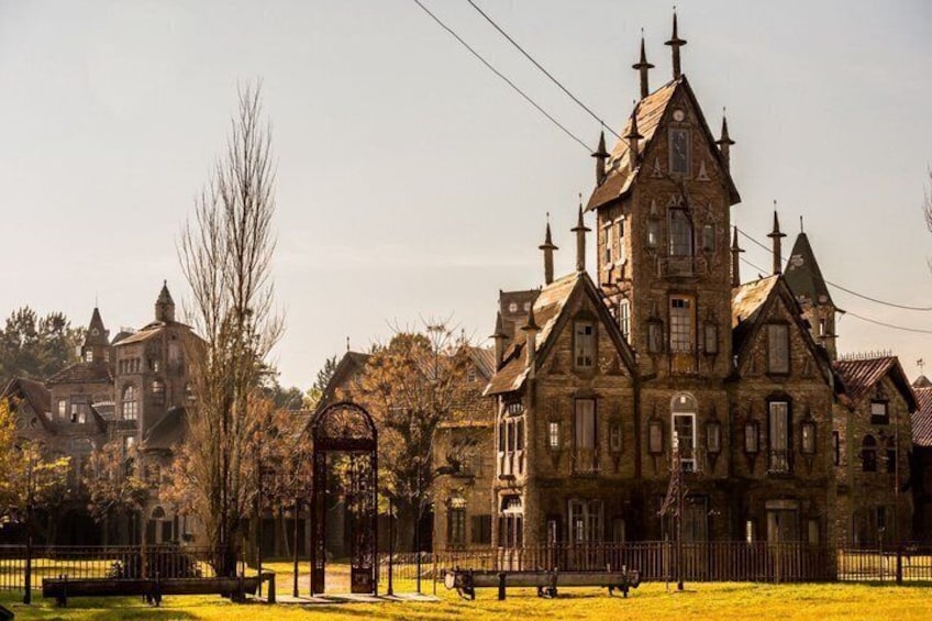 A large, historic building with multiple towers and a prominent entrance gate. 1
