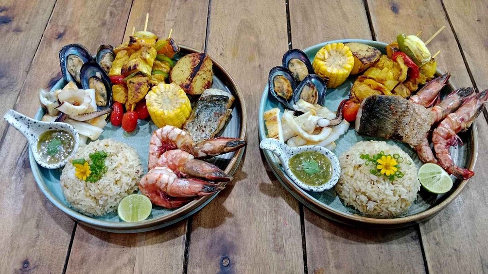 Two plates of seafood and grilled vegetables on a wooden table. 3