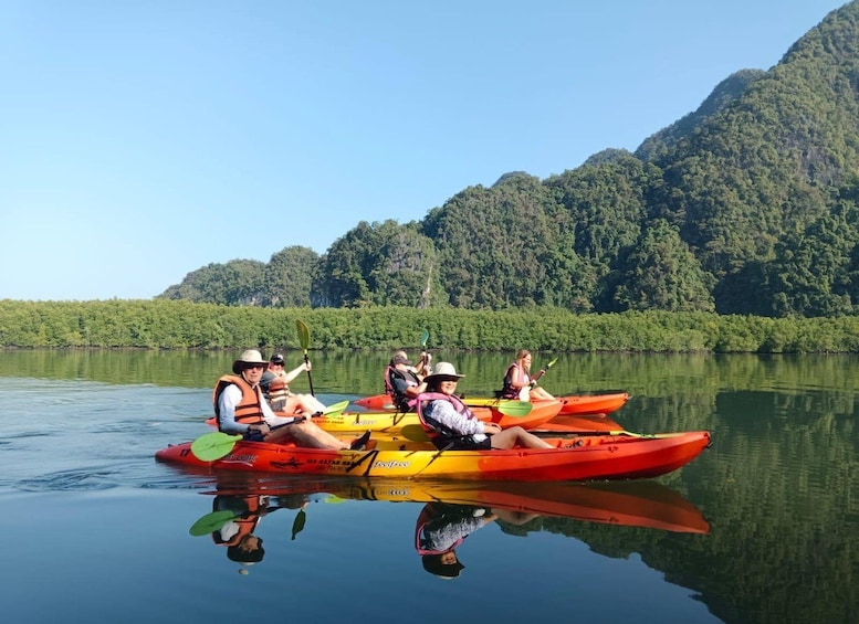 A group of people kayaking on a calm river surrounded by lush green hills. 1
