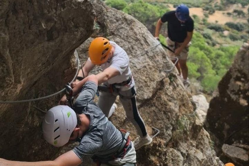 People climbing a rocky cliff with helmets and harnesses. 4