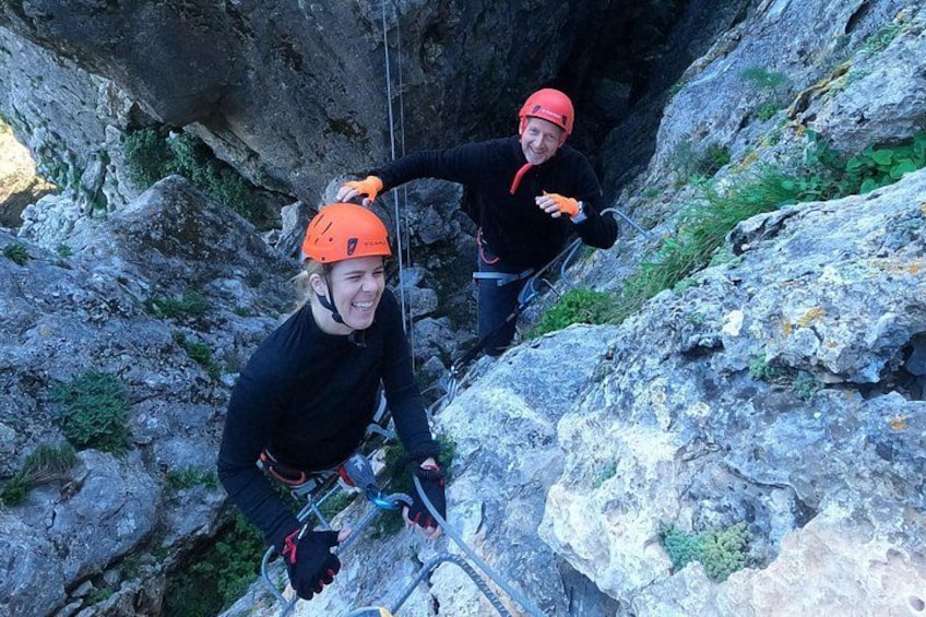 Two people rappelling down a rocky cliff. 3