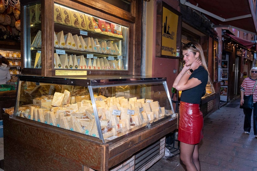 A cheese display in a shop window with various types of cheese on sale. 2