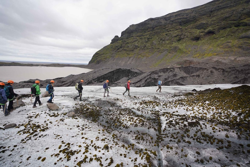 A group of hikers on a snowy trail with a glacier and a lake in the background. 4