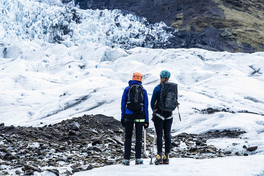 Two people hiking on a snowy mountain with a glacier in the background. 2