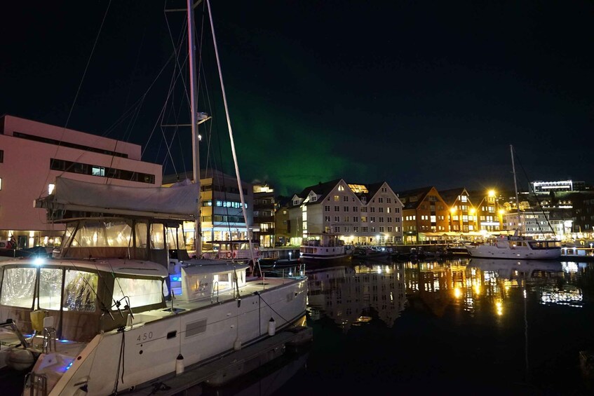 A marina at night with boats docked, buildings with lights, and the aurora borealis in the sky. 4