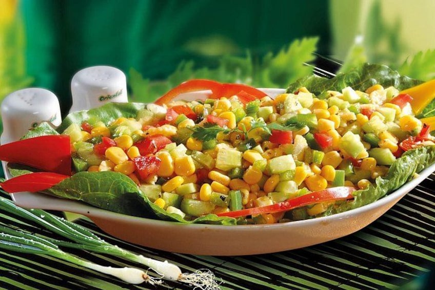 A salad with corn, tomatoes, and lettuce on a plate. 1