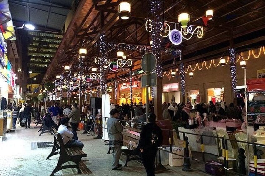 An indoor market with stalls, people shopping, and decorative lights. 5