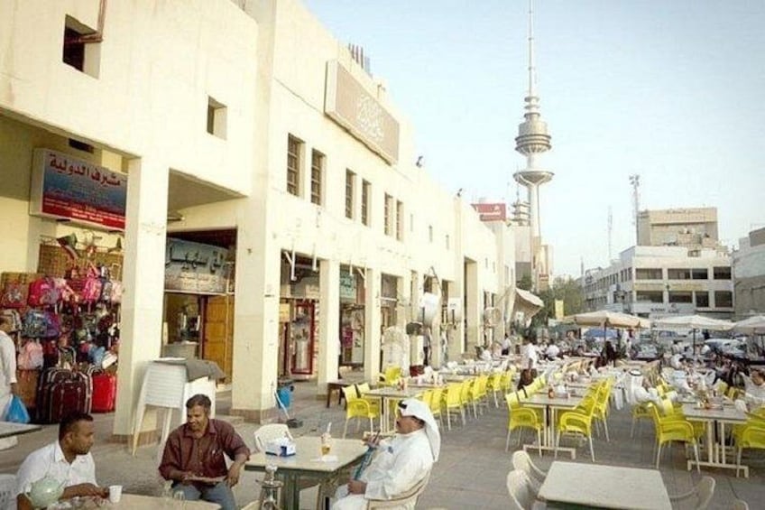 A street with outdoor seating, shops, and a tower in the background. 4