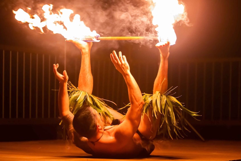 A performer balancing flaming torches on a stick while lying on the ground. 3