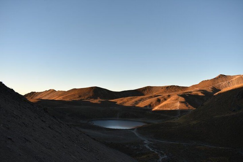 A mountainous landscape with a small lake surrounded by hills. 3