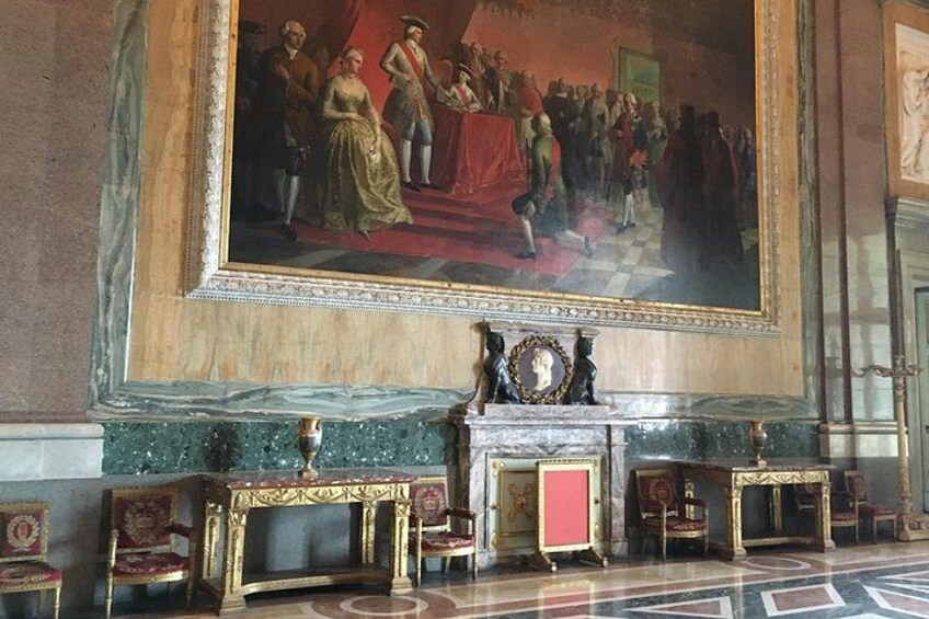 En storslagen hall med en stor, klassisk målning, utsmyckade möbler och ett marmorgolv. 2