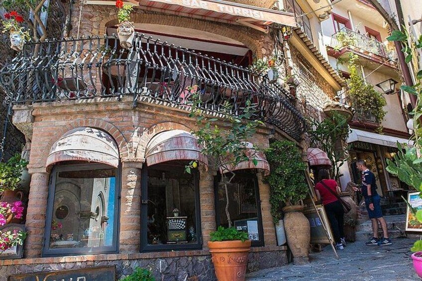 A building with a wrought iron balcony, potted plants, and a sign that reads 'TURISTI.' 4