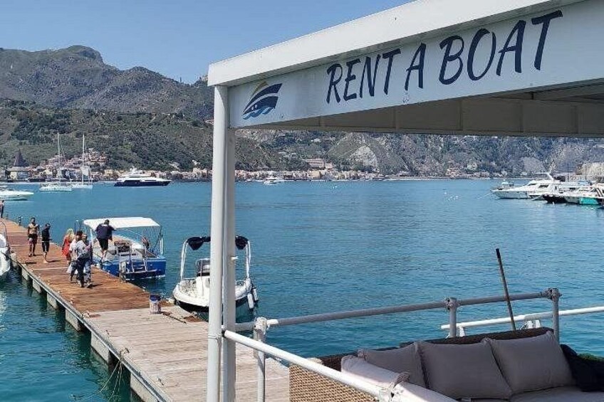 A boat rental service with a sign that reads 'RENT A BOAT' and a dock with people and boats. 2