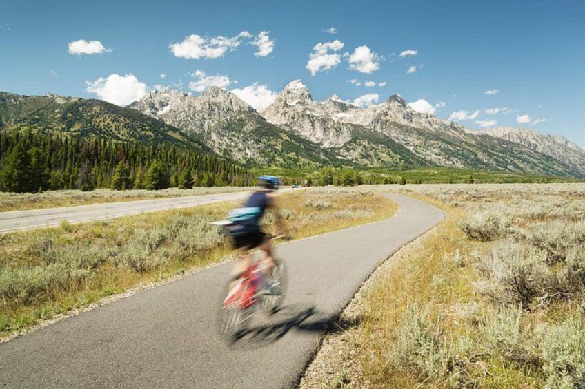 Un cycliste sur une route asphaltée, avec des montagnes en arrière-plan. 1