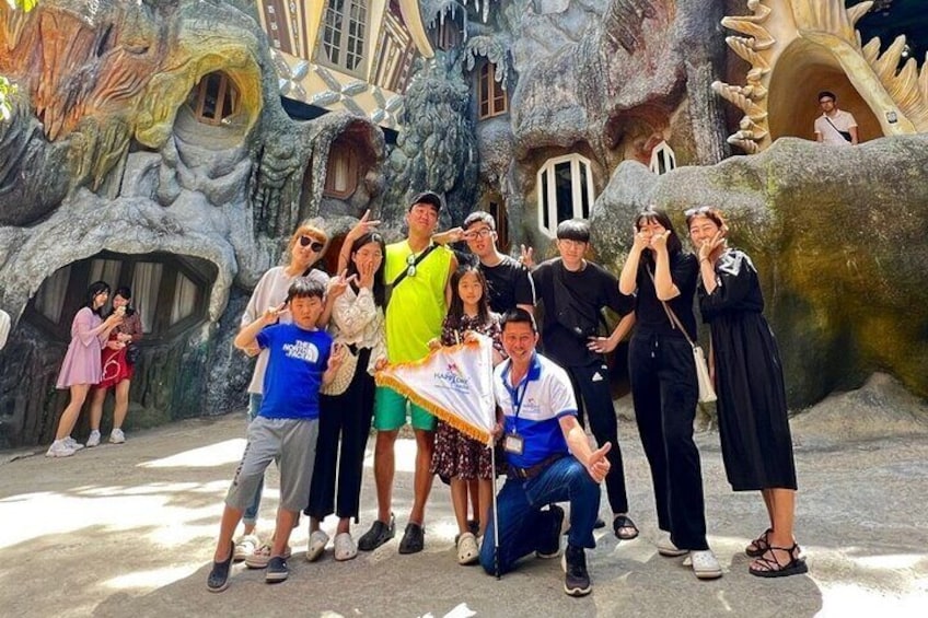 A group of people posing in front of a cave-like structure with a large, golden spiral design. 1