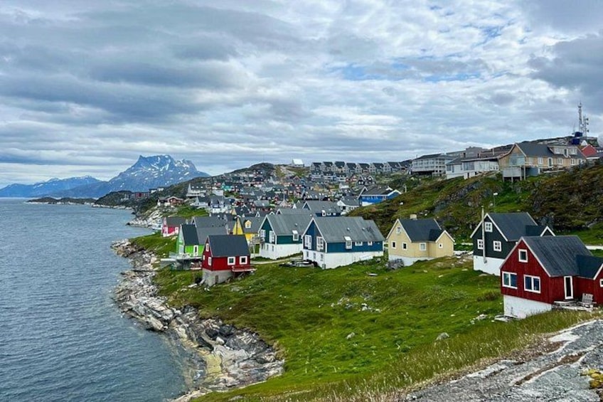 A coastal village with colorful houses, a rocky shoreline, and a mountain in the background. 3