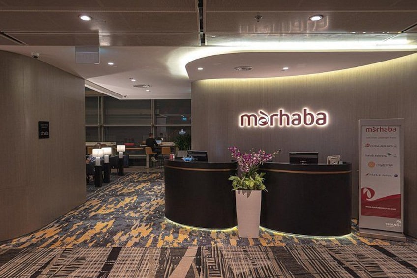 A reception area with a reception desk, a potted plant, and a signboard. 1