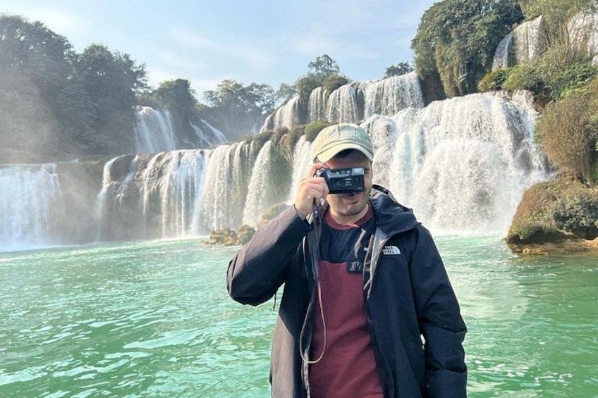 Eine Person fotografiert einen Wasserfall, an dem das Wasser einen steilen Felsen hinabfließt. 5