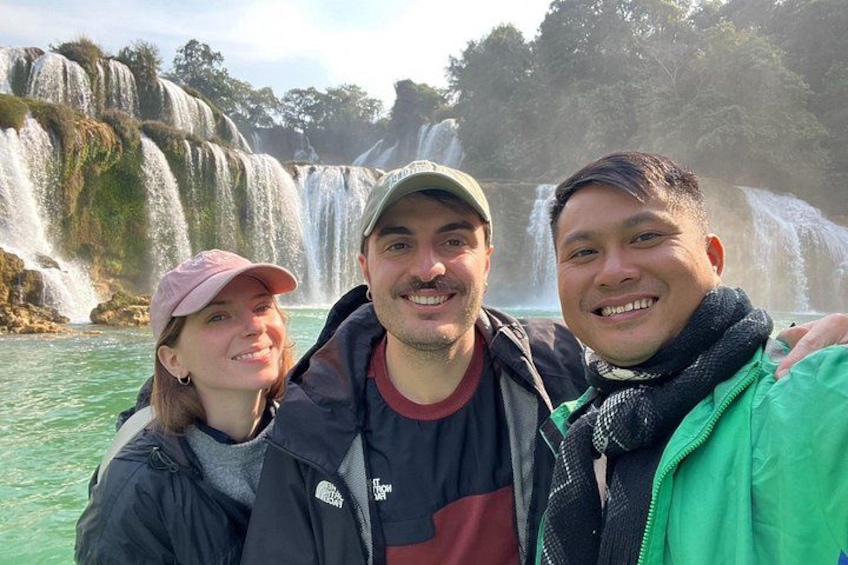 Drei Personen stehen vor einem Wasserfall, von dem Wasser über mehrere Stufen herabfließt. 1