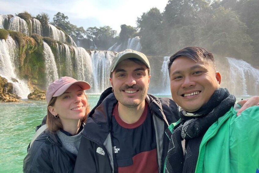 Drie personen staan voor een waterval. 1