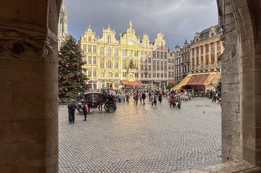 Een geplaveid plein met een kerstboom en een huifkar. 2