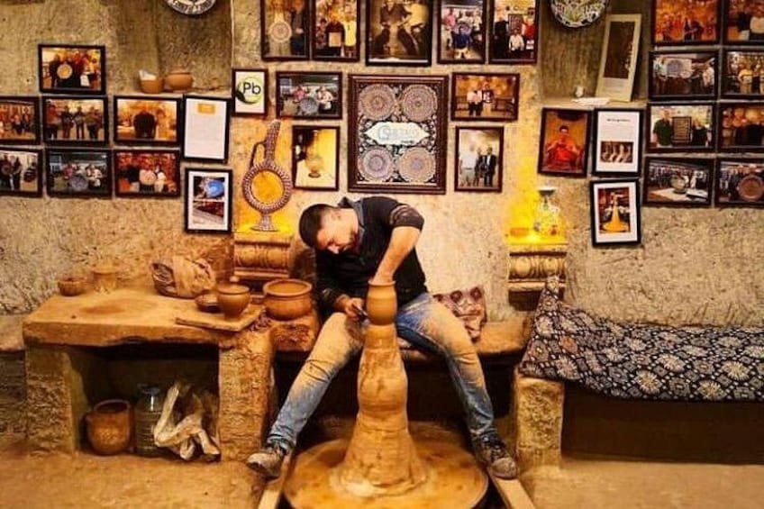 A person working on a pottery wheel in a room filled with pottery and photographs. 5