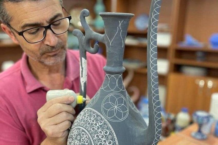 A person working on a ceramic vase with intricate patterns. 3
