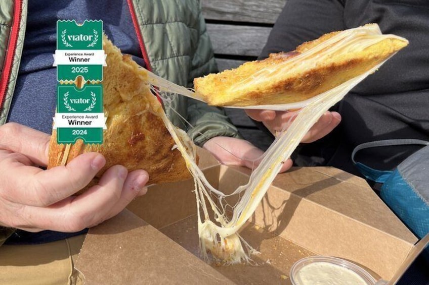 Una persona sosteniendo un sándwich con queso que se estira. 5