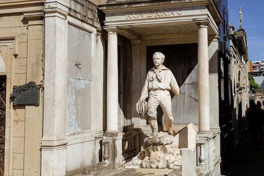Una estatua de un hombre con uniforme militar sobre un pedestal frente a un edificio con columnas. 2