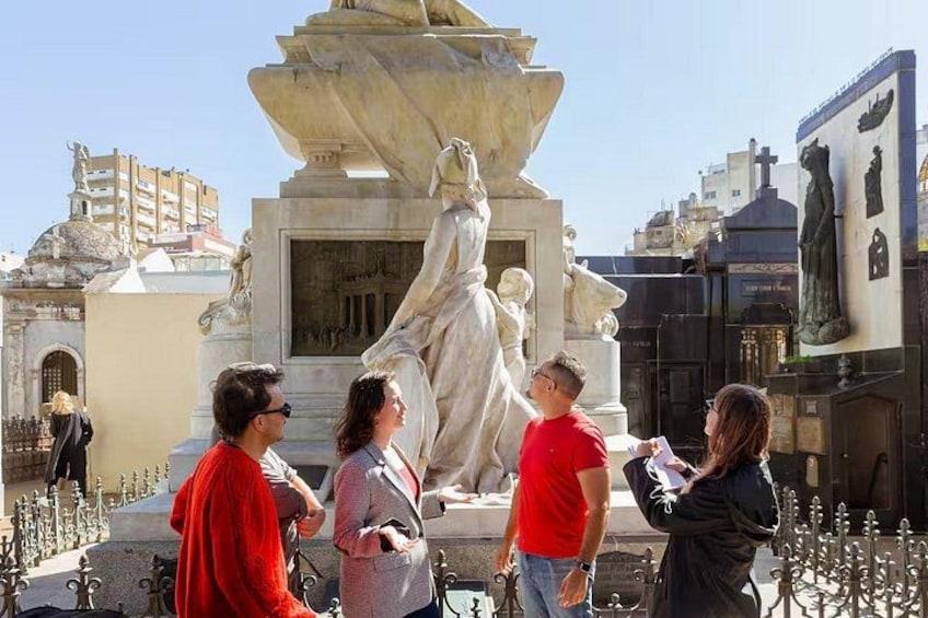 Un grupo de personas frente a una estatua grande con una fuente. 1
