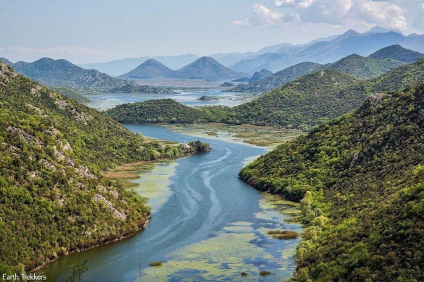 Une rivière serpentant à travers un paysage montagneux, bordé d’une végétation luxuriante. 1