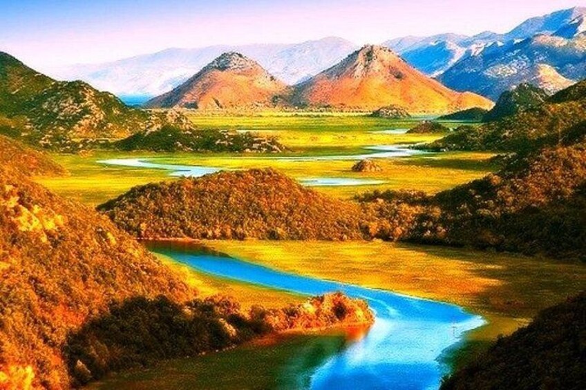 Un paysage montagneux avec une rivière, des champs verdoyants et des montagnes à l’horizon. 4